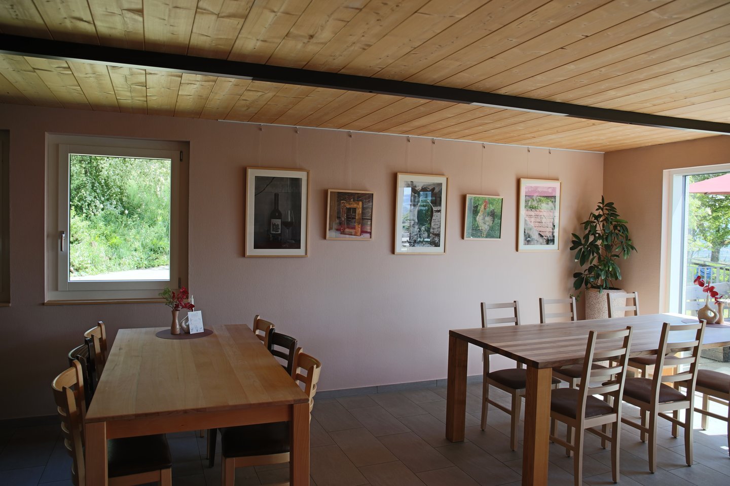 Heller Gastraum mit Bildergalerie an rosafarbener Wand